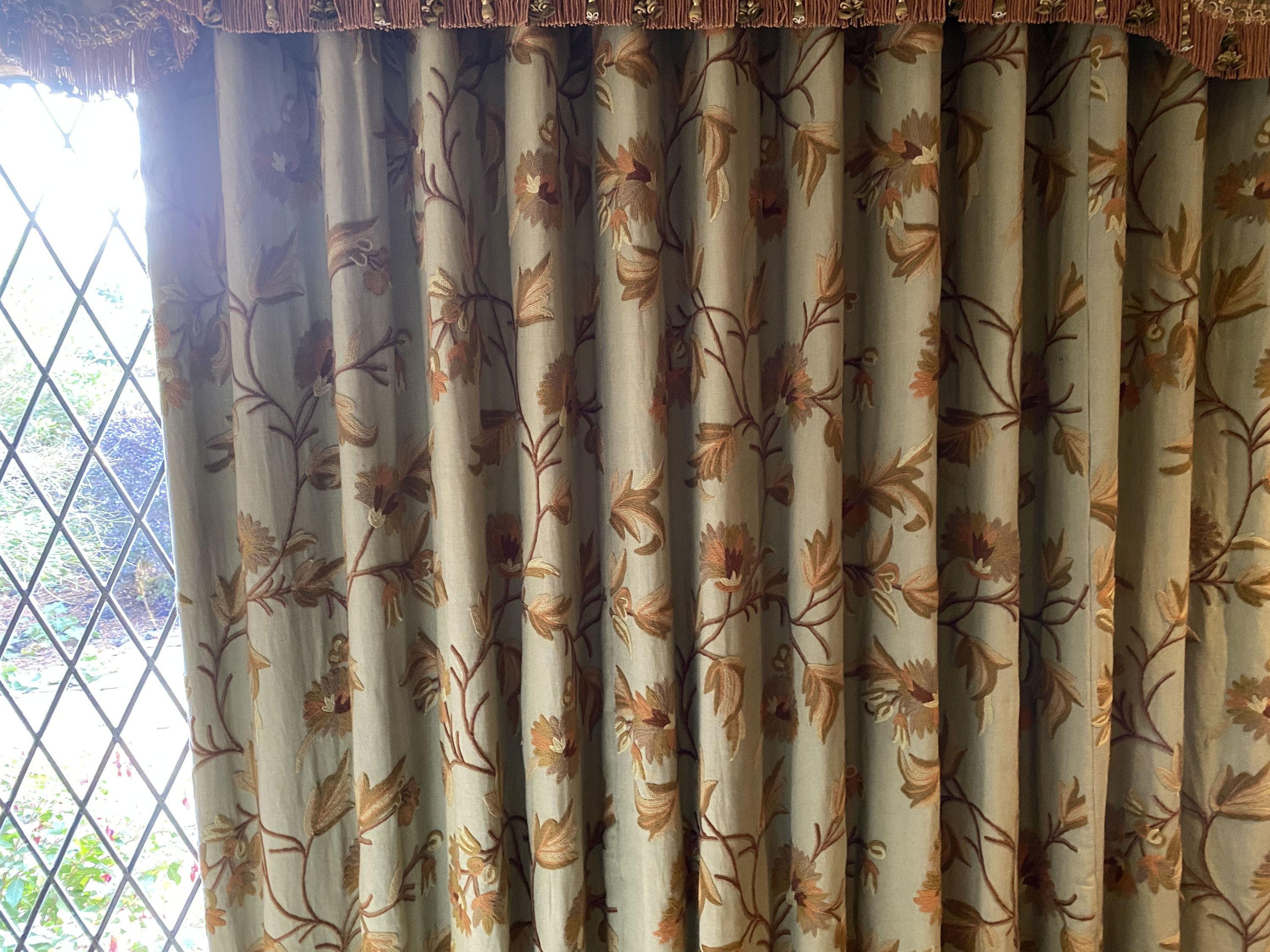 A pair of eau de nil linen curtains with floral crewel work decoration, and matching two piece pelmet, drop 230cm, generously made to fit an aperture of 3.8m